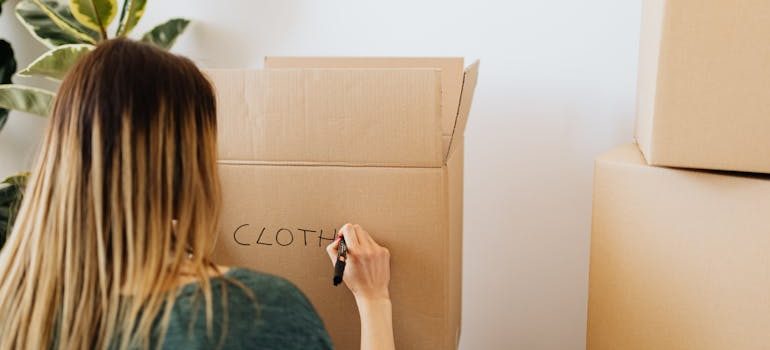 Woman packing stuff and writing on carton box