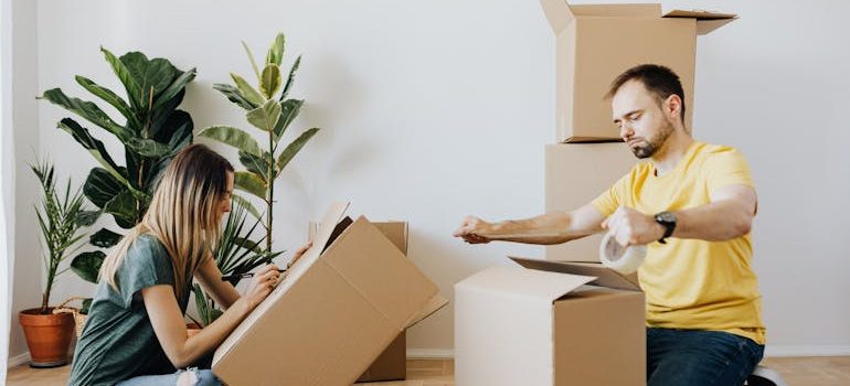 couple sealing carton boxes during renovation