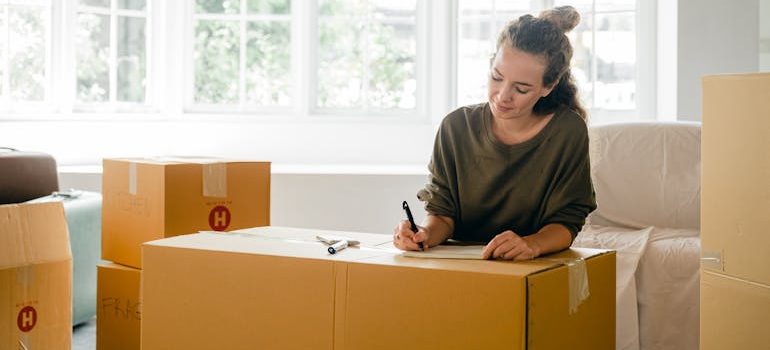 Woman signing box near large window in sunlight at home