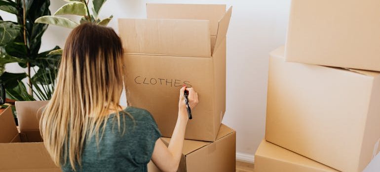 Woman writing on carton box word clothes